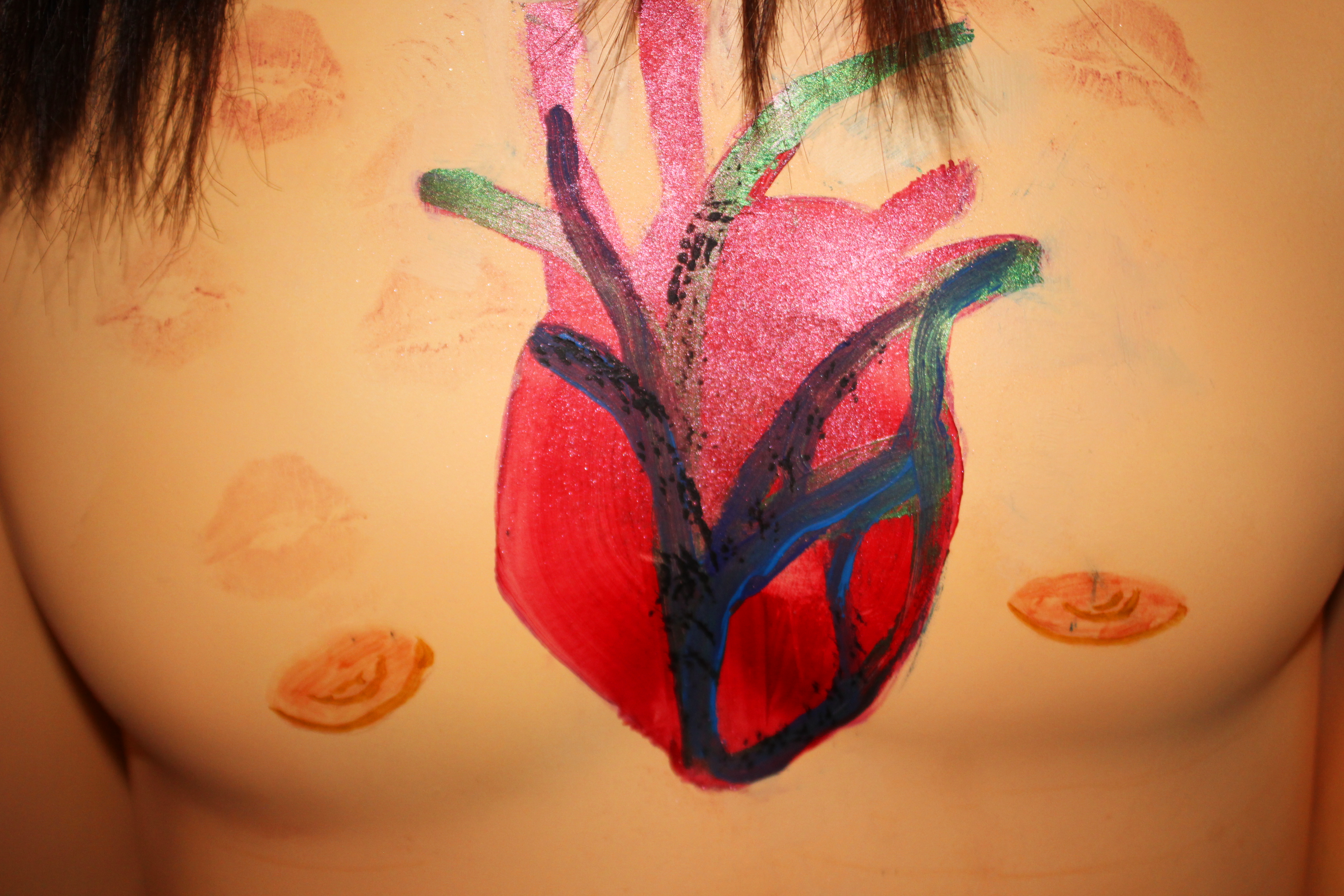 A photo of a man's chest, he has a large red and blue sparkly heart painted onto the middle of his chest